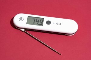 A digital meat thermometer measuring the temperature of a delicious seared ribeye steak.