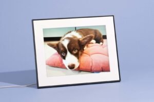 A modern digital picture frame displaying a landscape photograph on a wooden side table.