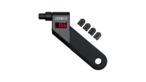 A person uses a digital tire pressure gauge on a car tire outdoors.