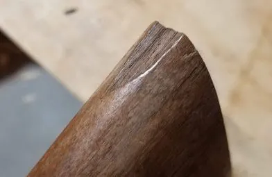Applying epoxy into a hole in a wooden gun stock using a toothpick.