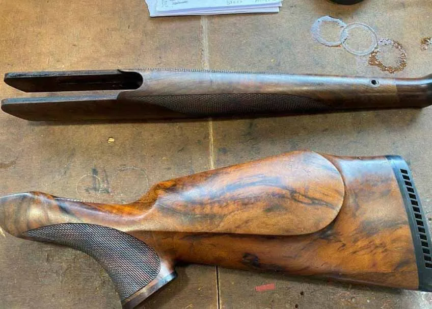 Detailed view of an enlarged screw hole in a wooden gun stock.