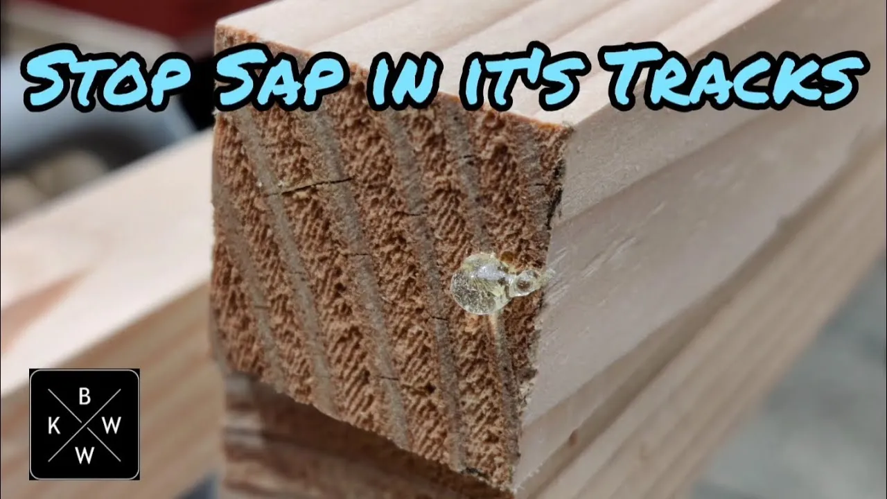 A gloved hand inspecting a sticky sap spot on a piece of wooden trim.