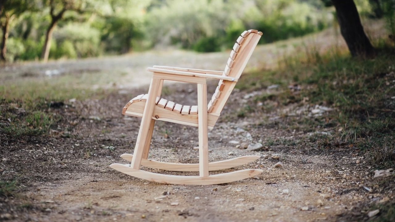 A handcrafted wooden rocking chair stands in a bright, modern woodworking studio workshop.