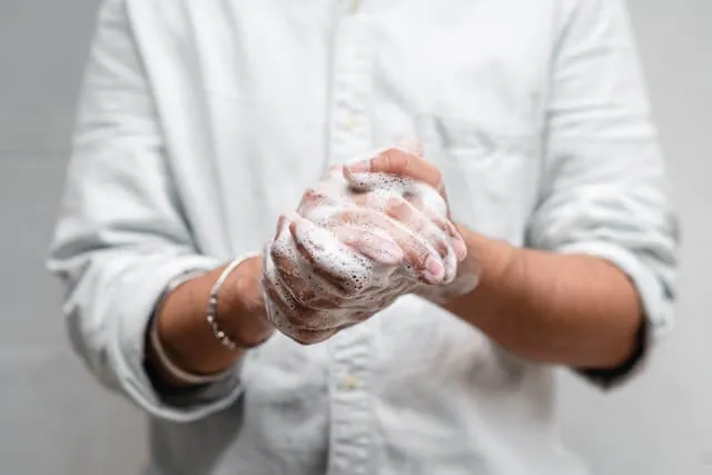 Hands being rinsed under water to soothe skin irritation from polyurethane removal efforts.
