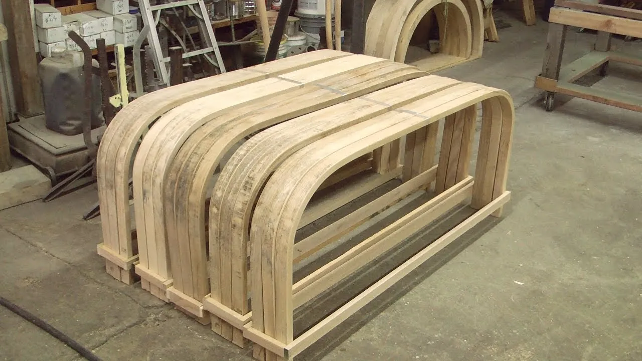 Hands secure a steaming piece of wood onto a jig using a strap.
