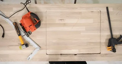 Marking a square outline on a wooden surface for a jigsaw project.