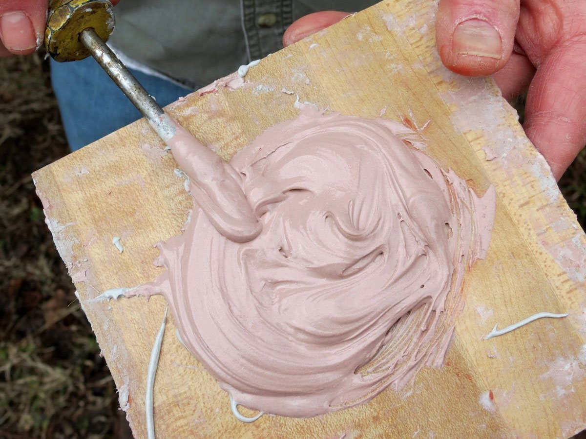 Mechanic applying automotive body filler to a car panel for a smooth repair.