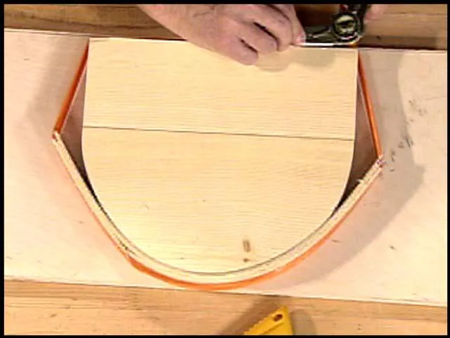 Multiple thin wood strips being laminated over a mold for a curved project.