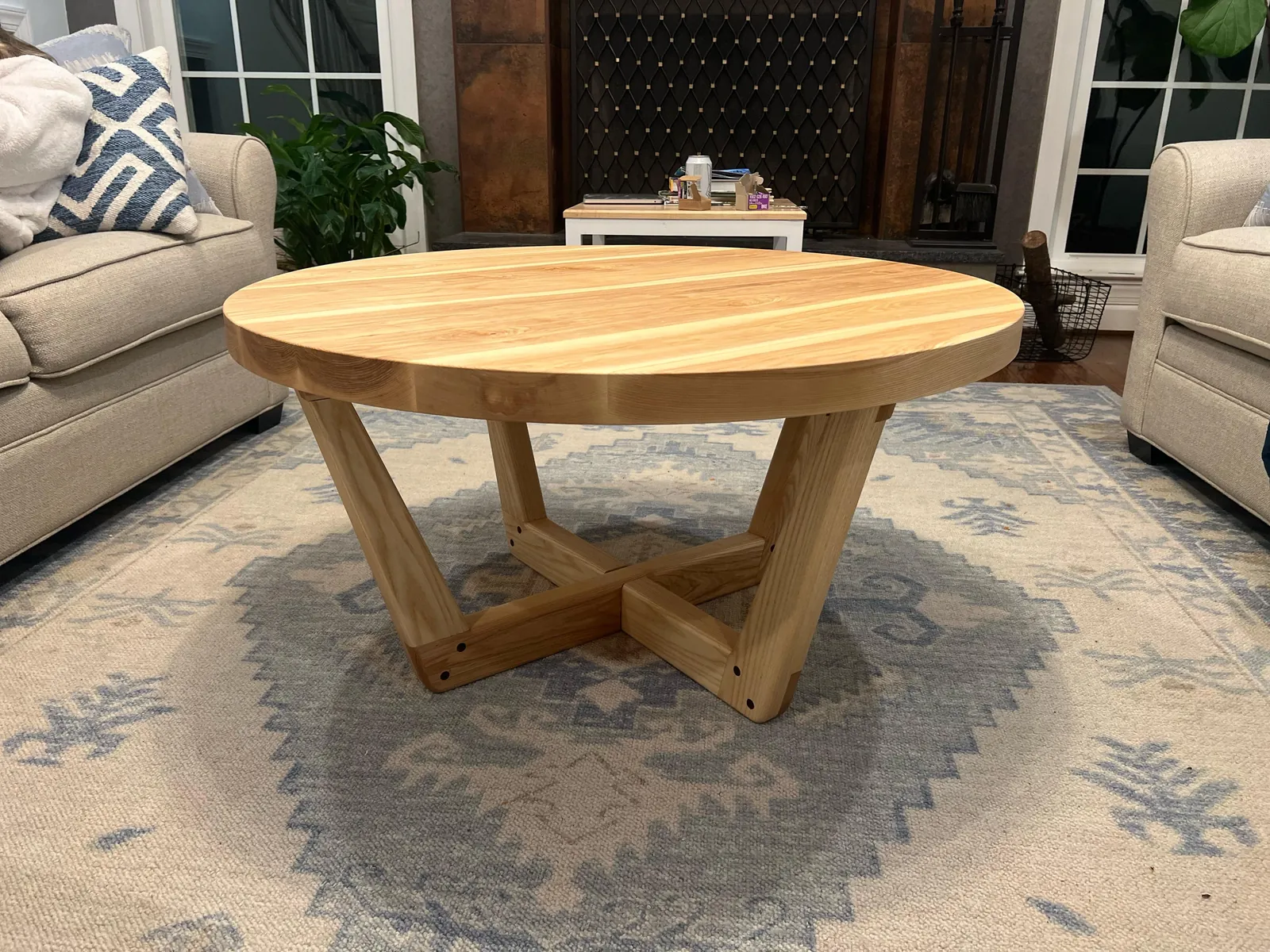A person measures the thickness of a wooden table in a home setting.