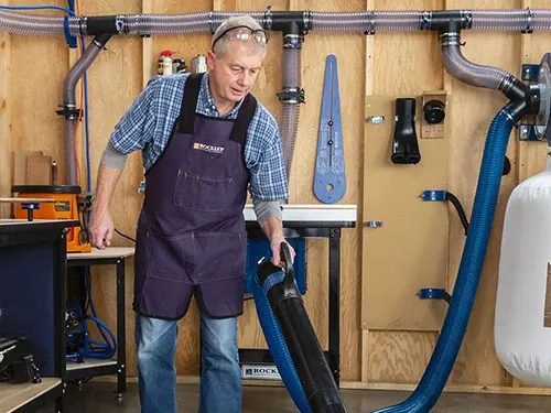 Portable dust collection hose connected to a machine in a small workshop.