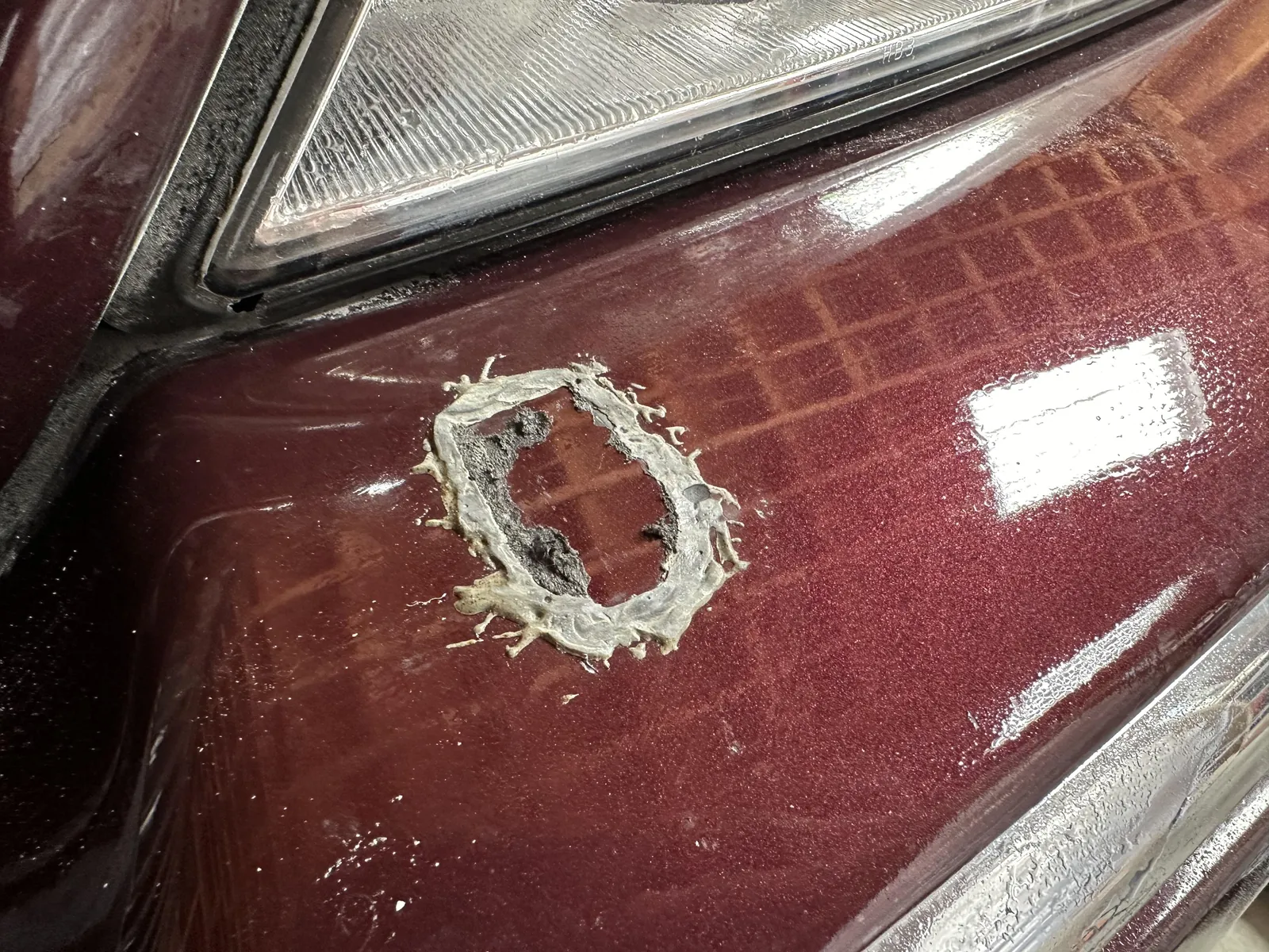 Sanding cured JB Weld from a metal surface in a clean workshop setting.