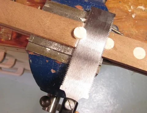 Sanding the end of a wooden dowel with a block to ensure a flat finish.