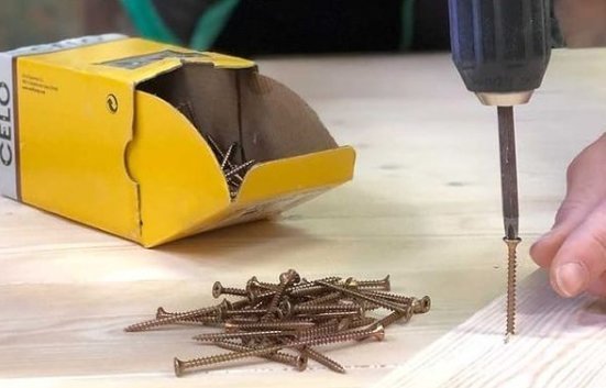 A stainless steel self-tapping screw inserted into a piece of oak wood.