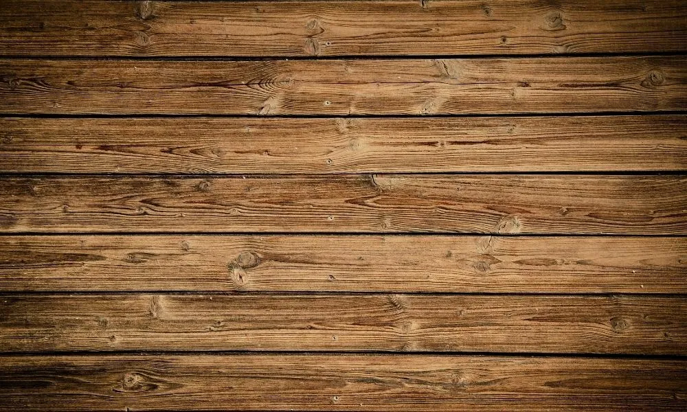 A steel tool used for burnishing wood resting on a smooth maple surface.