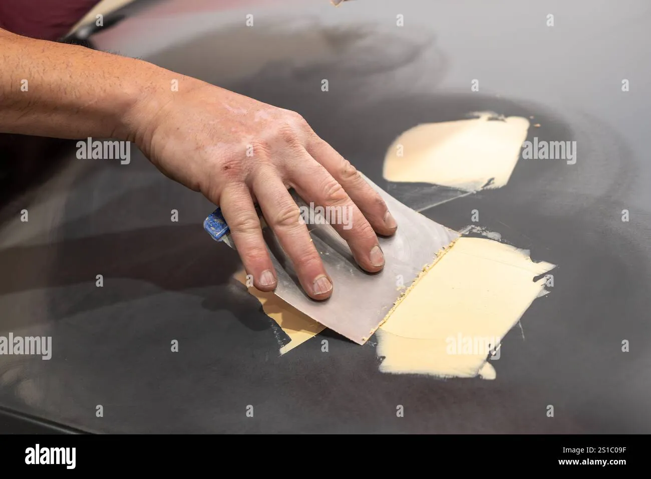 Using a hair-dryer to warm a car panel to ensure proper filler curing.