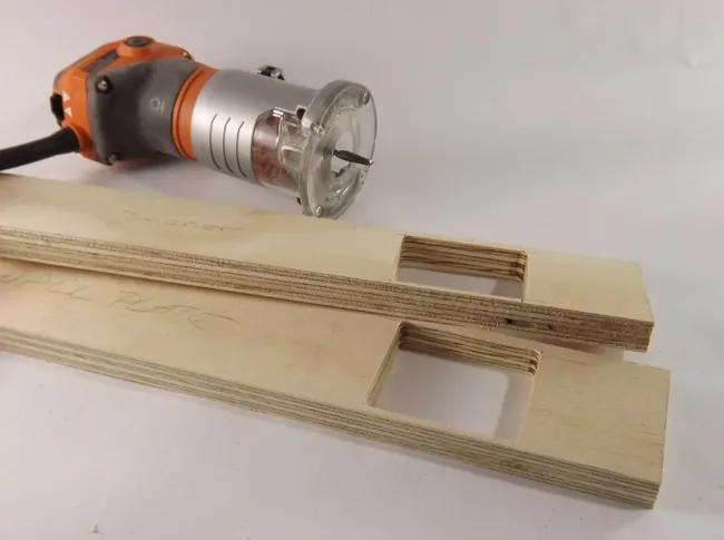 A woodworker preparing to use a plunge router on a wooden board.