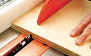 A woodworking table saw cutting a precise groove into a piece of oak.