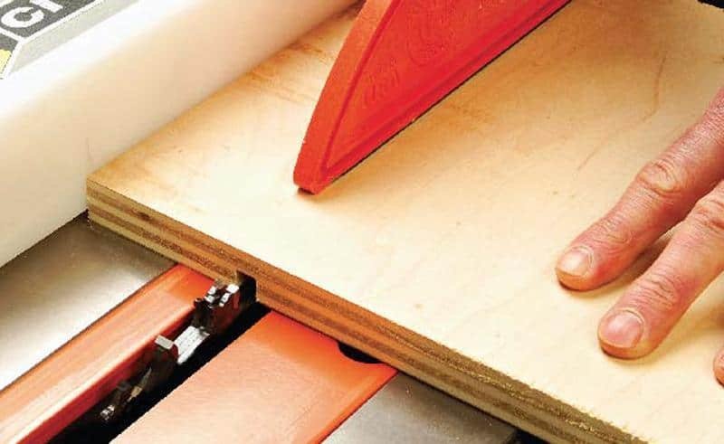 A woodworking table saw cutting a precise groove into a piece of oak.